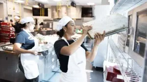 Greis Iriarte (left) and America Salon, students in the inaugural cohort of the WorkReady labor-integration program, put away pans in the School of Hospitality kitchen.